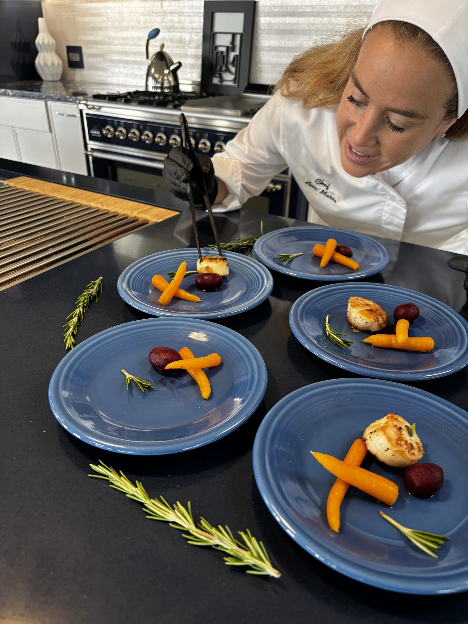 A female chef plating a meal in a kitchen.| ANA MARIA'S CATERING