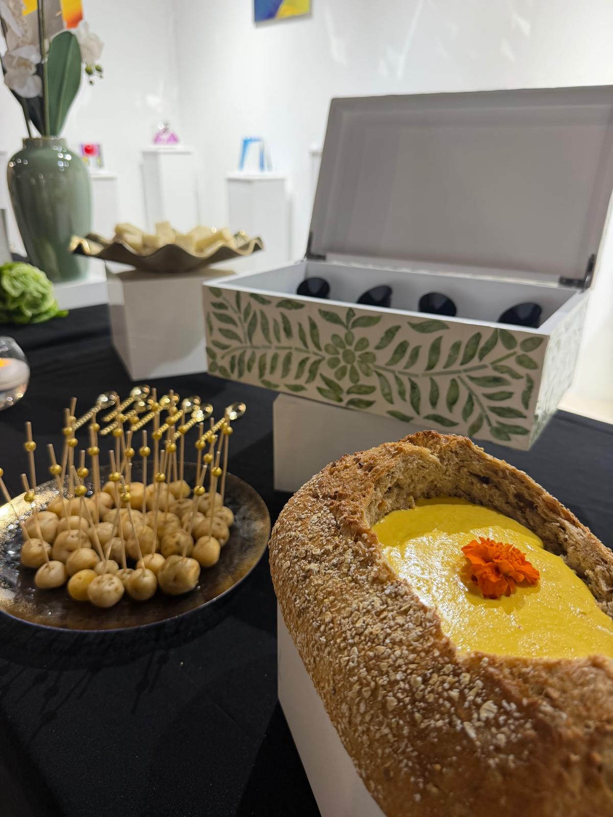 Bread bowl of yellow soup with gold cocktail picks