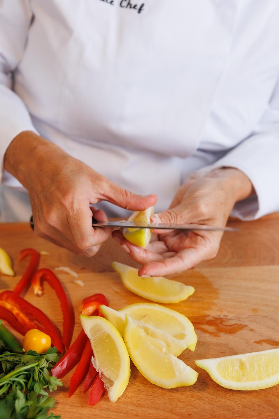Chef slicing fresh lemon and peppers in the kitchen