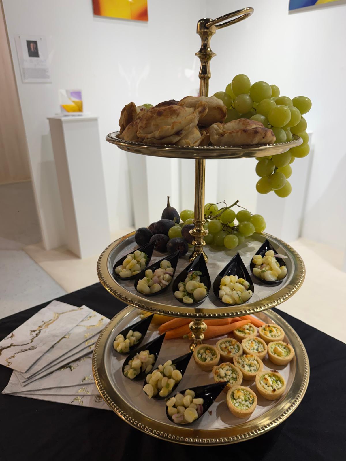 Gold tiered display of empanadas and ceviche spoons